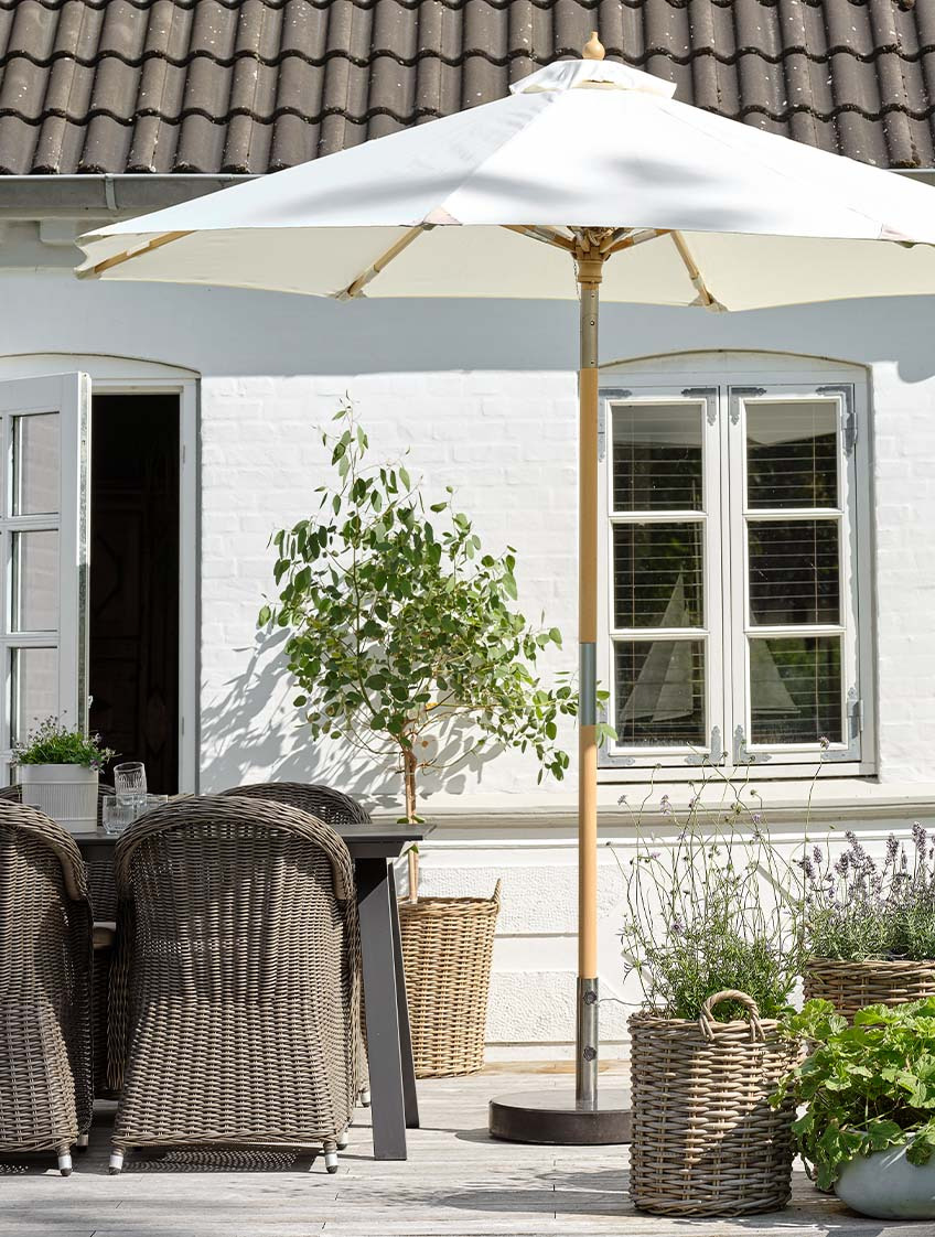 Guarda-sol de jardim clássico em branco no pátio com mesa e cadeiras de jardim